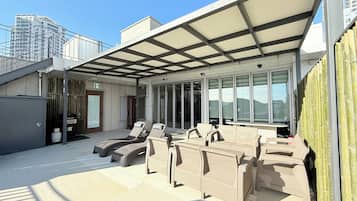 Una terraza en la azotea con mobiliario exterior y una zona cubierta.