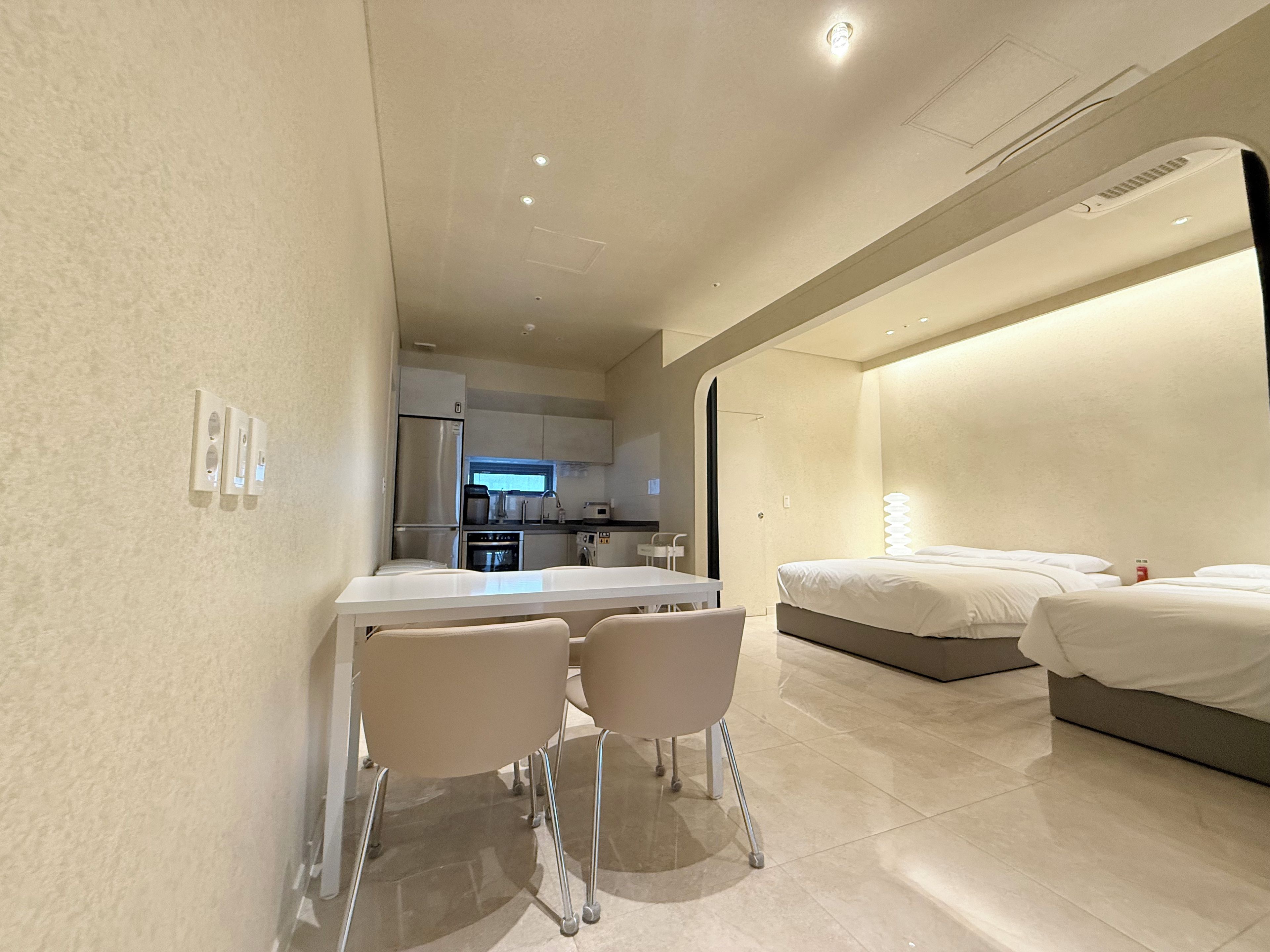 Una habitación de hotel moderna con kitchenette, un comedor con sillas y una cama.