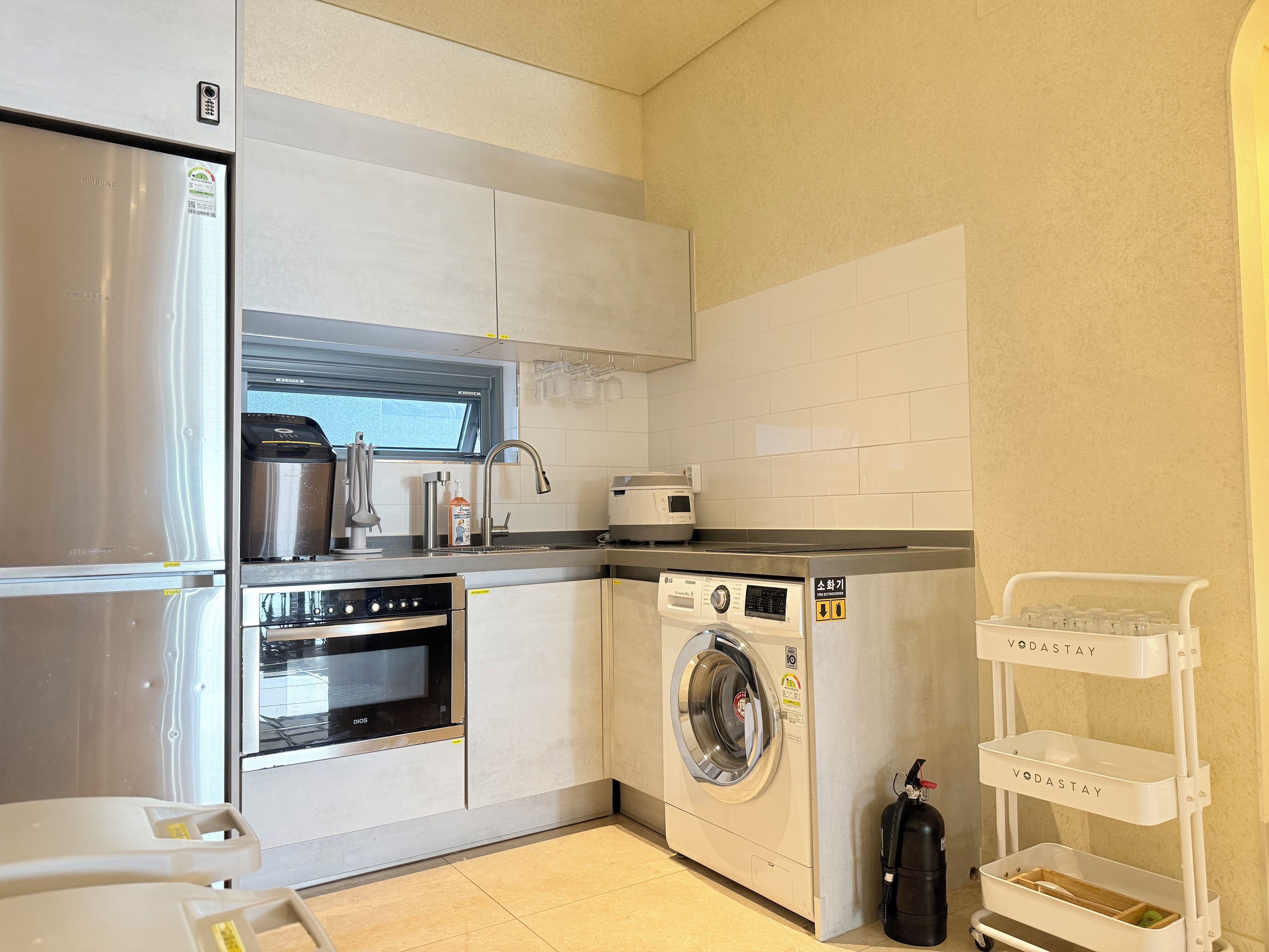 Una cocina compacta equipada con refrigerador, horno, microondas y lavadora.