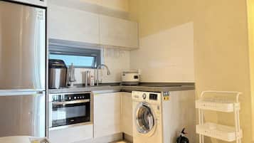 Una cocina compacta equipada con refrigerador, horno, microondas y lavadora.