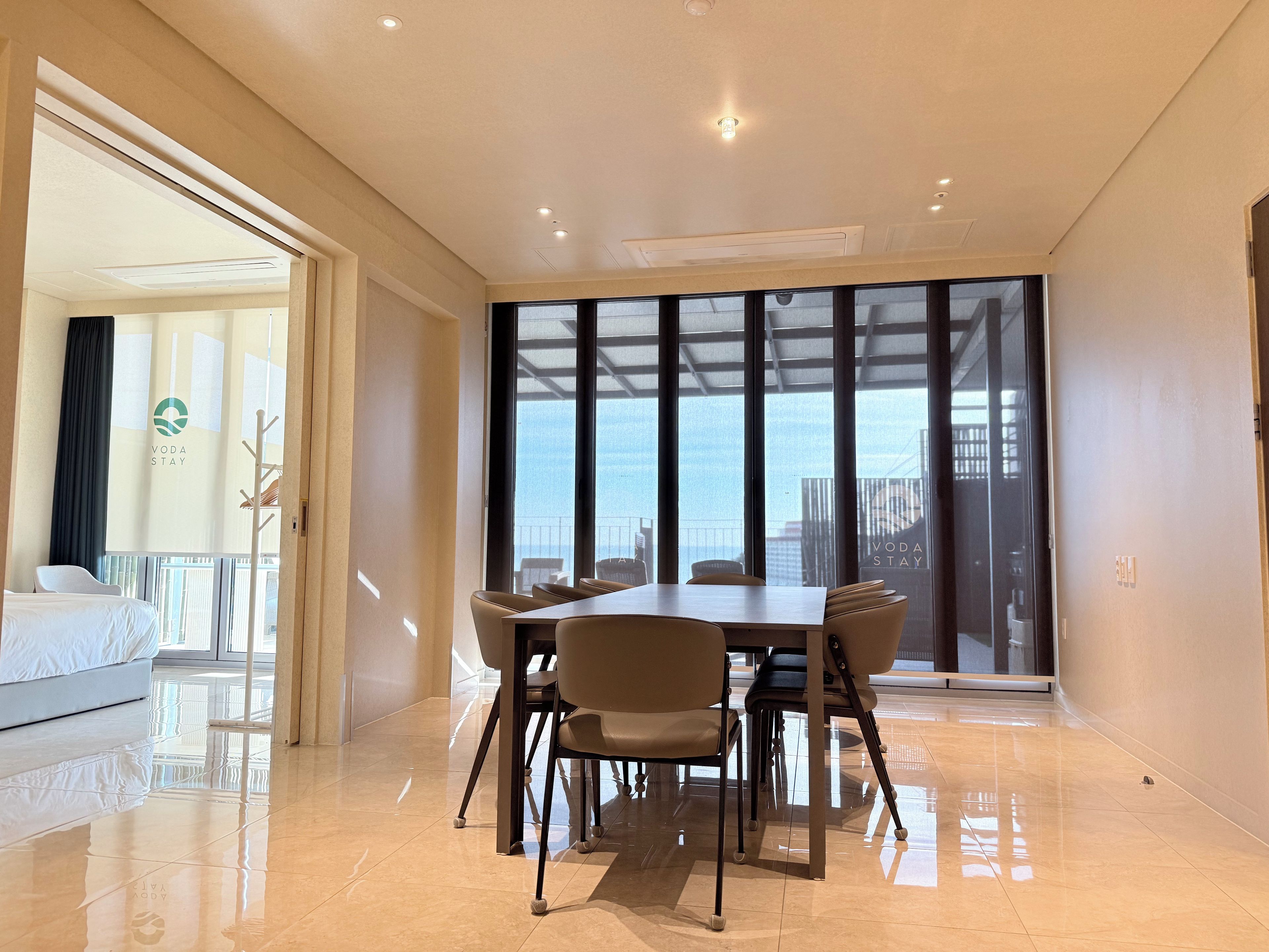 Habitación de hotel con comedor, ventanas amplias y vistas a la ciudad.