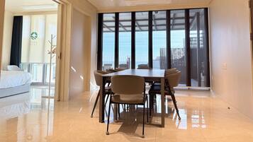 Habitación de hotel con comedor, ventanas amplias y vistas a la ciudad.