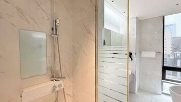 A modern bathroom with a glass shower enclosure, a towel rack, and a large mirror.