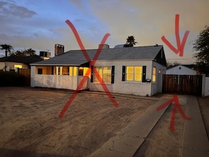 A single-story house with a fenced yard, a visible garage, and a clear sky. - Moreland Guesthouse (Phoenix)
