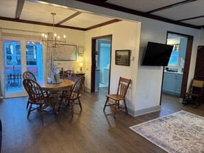 A dining area with a wooden table and chairs, a chandelier, and a map on the wall.