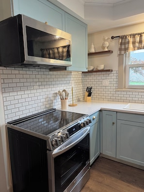 A kitchen with a built-in microwave, stove, oven, and a window with a view.