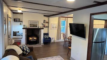 A living room with a fireplace, a television, and a modern kitchen area.