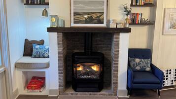 Una sala de estar acogedora con chimenea, estanterías, un banco y un sillón azul.