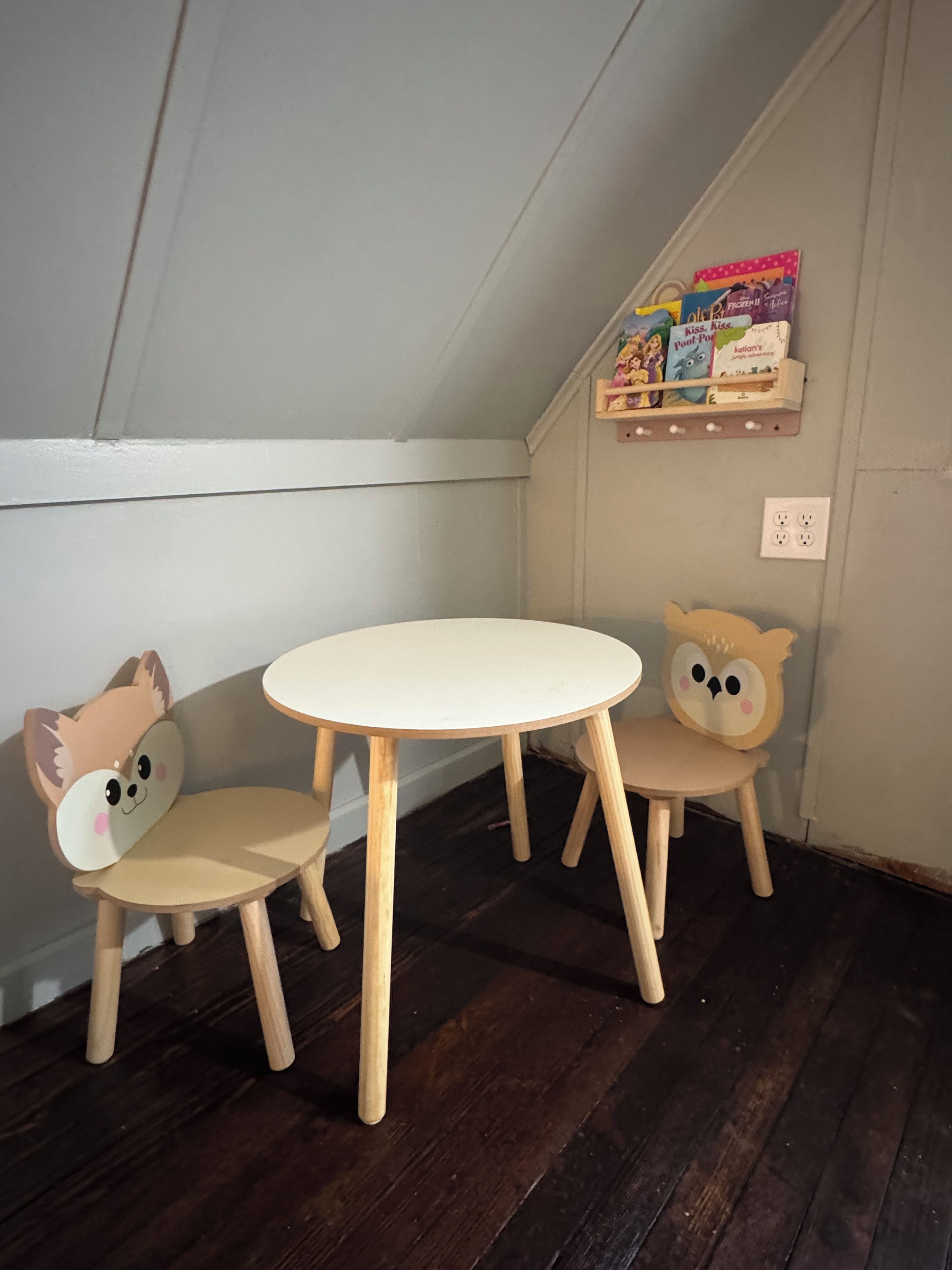 Ein Eckzimmer mit weißer Decke, Holzboden und zwei Stühle aus Holz mit Tiermotiven.