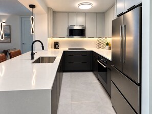 Een moderne keuken met een roestvrijstalen koelkast, een inbouwmagnetron en een koffiezetapparaat.