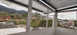 A room with a large window offering a view of a mountainous landscape and a village below. - Casa LuzErick hospedaje  (Calima)