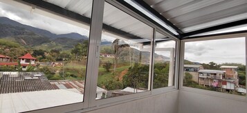 Habitación con un amplio ventanal que ofrece vistas a un paisaje montañoso y un pueblo en la ladera.