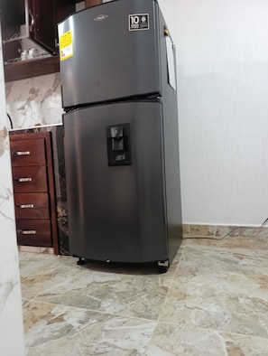 Un refrigerador negro con dispensador de agua, una etiqueta conmemorativa del décimo aniversario y un panel de control.