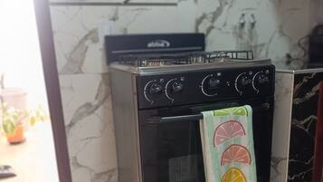 Una cocina con horno negro, salpicadero de mármol y una toalla con motivos de cítricos.