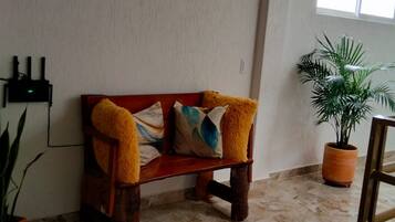 A room with a wooden bench, a potted plant, and a tiled floor.