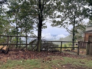 A fenced outdoor area with trees and a view of a mountainous landscape.