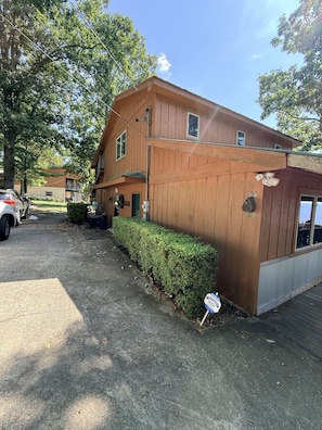 A two-story wooden house with a garage, a driveway, and a well-maintained hedge.