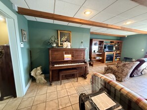 A living room with a piano, a couch, and a television.