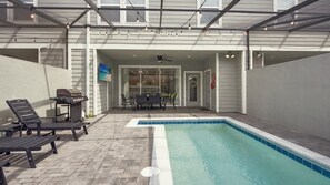 Ein Poolbereich mit Grill, Liegestühlen und einer überdachten Terrasse.