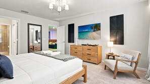 Ein Schlafzimmer mit einem großen Bett, einer hölzernen Kommode, einem Stuhl und einem Bild von einem Strand.