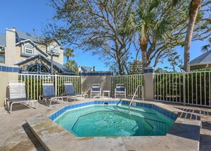 A swimming pool with lounge chairs and a fence, surrounded by trees and a building. - Ground-Floor Sun Beach Club, 2 Kings, Pool and Hot Tub, Walk to Car-Free Beach (New Smyrna Beach)