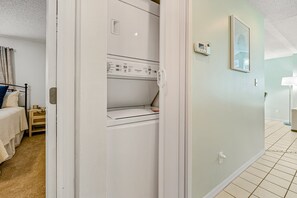 A room with a bed, a nightstand, a wall-mounted heater, a framed picture, and a tiled floor. - Ground-Floor Sun Beach Club, 2 Kings, Pool and Hot Tub, Walk to Car-Free Beach (New Smyrna Beach)