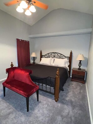 A bedroom with a bed, two bedside tables, a red chair, and a ceiling fan. - Beautiful Tri-Level. Spacious Comfort for Families and Groups. (El Paso)
