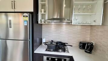 Cozinha moderna com geladeira de aço inoxidável embutida, fogão a gás e micro-ondas.