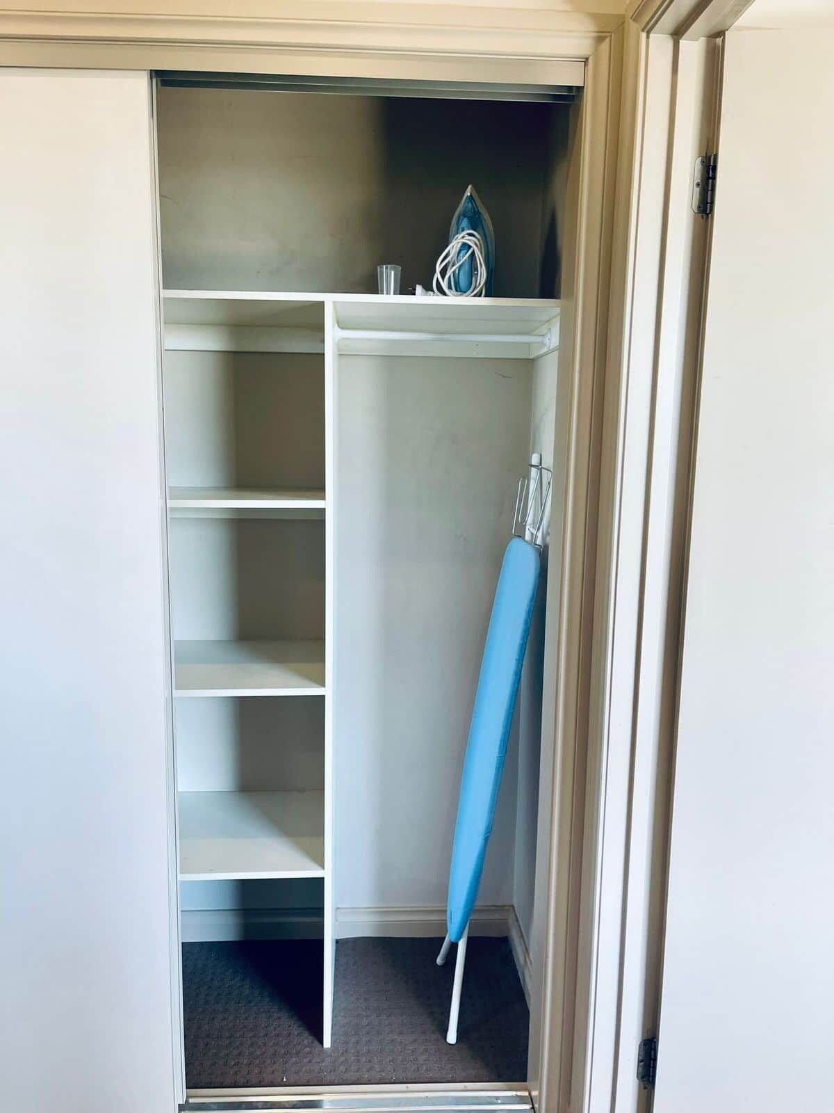 Um closet amplo com diversas prateleiras e cabideiro.