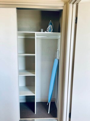 Um closet amplo com diversas prateleiras e cabideiro.