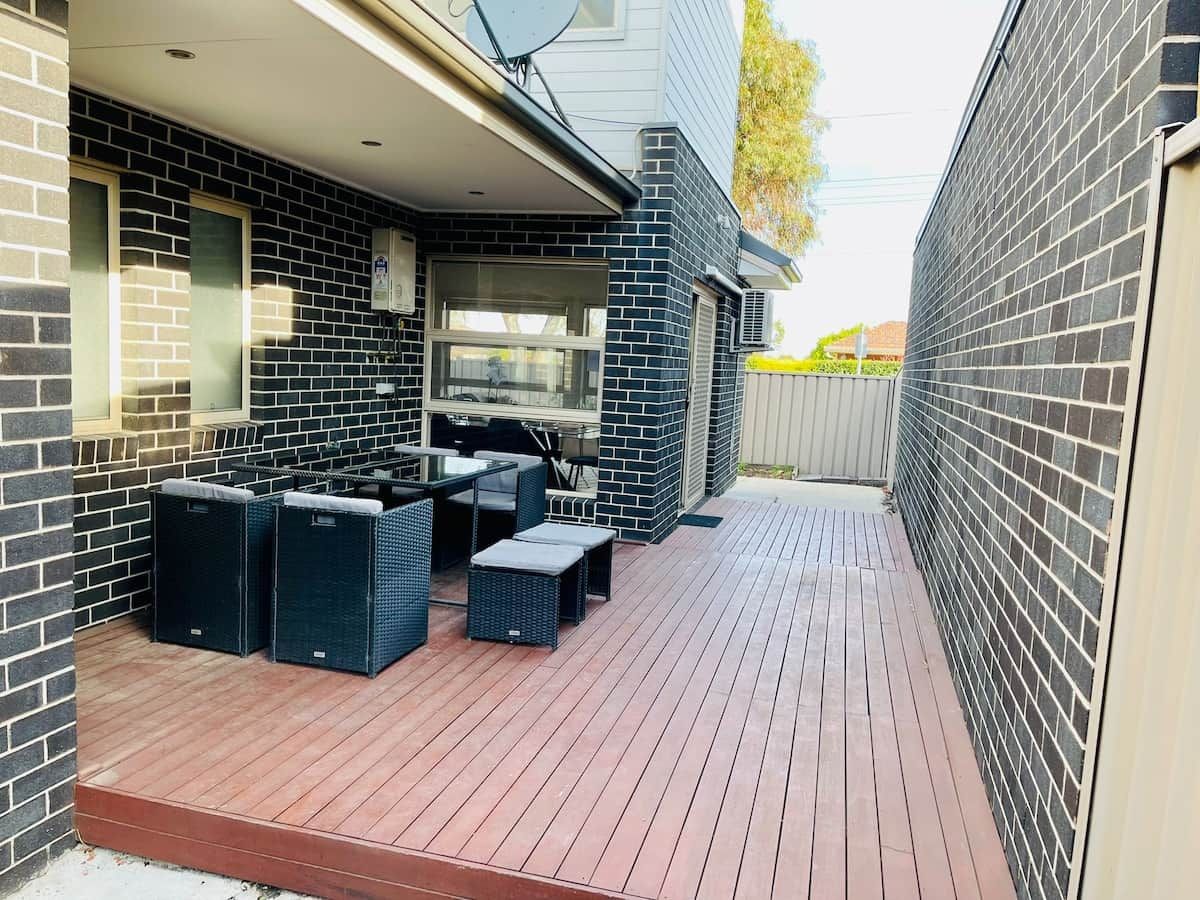 An outdoor patio with a barbecue area, seating, and a brick wall.