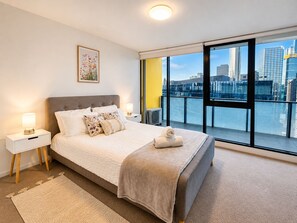 A modern hotel room with a large bed, a city view, and a balcony. - Skyline Views 1BR Opp Crown w/Free Parking (Southbank)