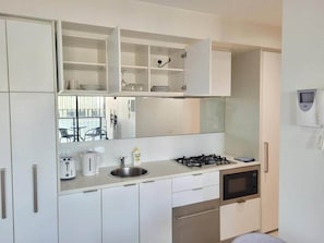 A modern kitchen with white cabinetry, a gas stove, a microwave, and a sink. - Skyline Views 1BR Opp Crown w/Free Parking (Southbank)