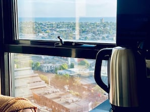 A window with a view of a cityscape, a coffee maker on the windowsill, and a towel on the floor. - Stunning Stay Steps away from Crown w/Free Parking (Southbank)