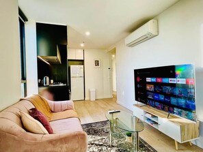 A modern living room with a flat-screen TV, a glass coffee table, and a sofa. - Stunning Stay Steps away from Crown w/Free Parking (Southbank)