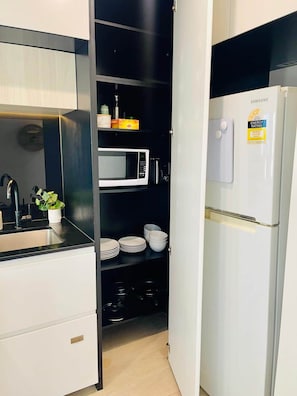 Cozinha compacta com micro-ondas, geladeira e pia.
