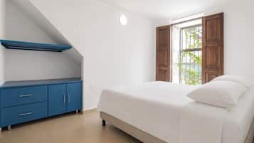 Ein Schlafzimmer mit einem Bett, einer blauen Kommode und einem Fenster mit Blick.