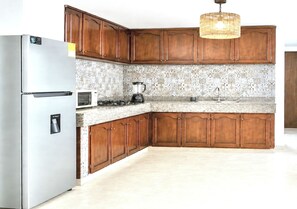 Una cucina con mobili in legno, un frigorifero in acciaio inossidabile, un forno a microonde, un frullatore e un lavandino.