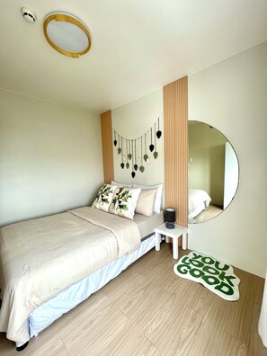 A bedroom with a bed, bedside table, mirror, and a wall-mounted decoration. - Cozy Staycation • Free Parking • 300Mbps WiFi • Taytay, Rizal (Taytay)