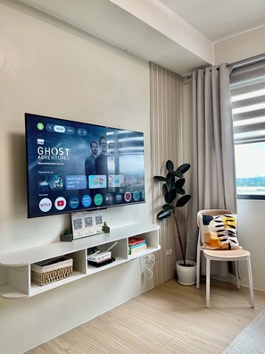 A modern living room with a flat-screen TV mounted on the wall displaying a movie recommendation. - Cozy Staycation • Free Parking • 300Mbps WiFi • Taytay, Rizal (Taytay)