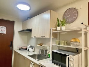 A compact kitchen with a microwave, sink, and a clock on the wall. - Cozy Staycation • Free Parking • 300Mbps WiFi • Taytay, Rizal (Taytay)