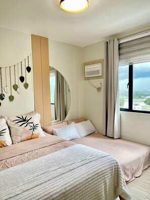 A bedroom with two beds, a mirror, a wall-mounted air conditioner, and a window with curtains. - Cozy Staycation • Free Parking • 300Mbps WiFi • Taytay, Rizal (Taytay)