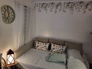 A bedroom with a bed, a wall clock, and a decorative floral wall hanging. - Cozy La Bella Tagaytay Stay Pool View + Work Space (Tagaytay City)