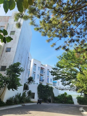A multi-story building with a white facade, balconies, and a clear sky.