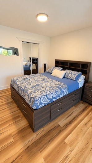 A bedroom with a bed, wooden floor, a wardrobe, and a mirror. - Vintage & lumineux • Secteur calme (Montréal)