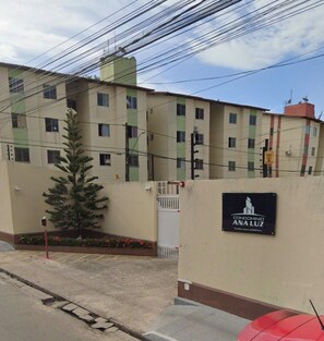 A residential building with a gated entrance, a sign indicating 'CONDOMINIO ANA LUZ,' and a tree in the foreground. - 2-Bedroom Apartment in the Central Area of ​​São Luís, MA. (São Luís)