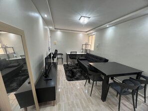 A modern living room with a sofa, a coffee table, a TV, and a dining area with chairs and a table. - 2-Bedroom Apartment in the Central Area of ​​São Luís, MA. (São Luís)
