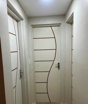 A hallway with a white door featuring a curved line design. - 2-Bedroom Apartment in the Central Area of ​​São Luís, MA. (São Luís)