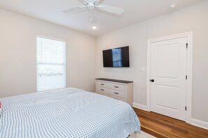 A bedroom with a bed, a dresser, a television, and a door. - Rebel Retreat - Close to the Square, Campus and MTrade Park! (Oxford)