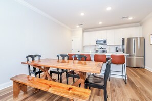 A modern kitchen with white cabinets, stainless steel appliances, and a wooden dining table with chairs. - Rebel Retreat - Close to the Square, Campus and MTrade Park! (Oxford)